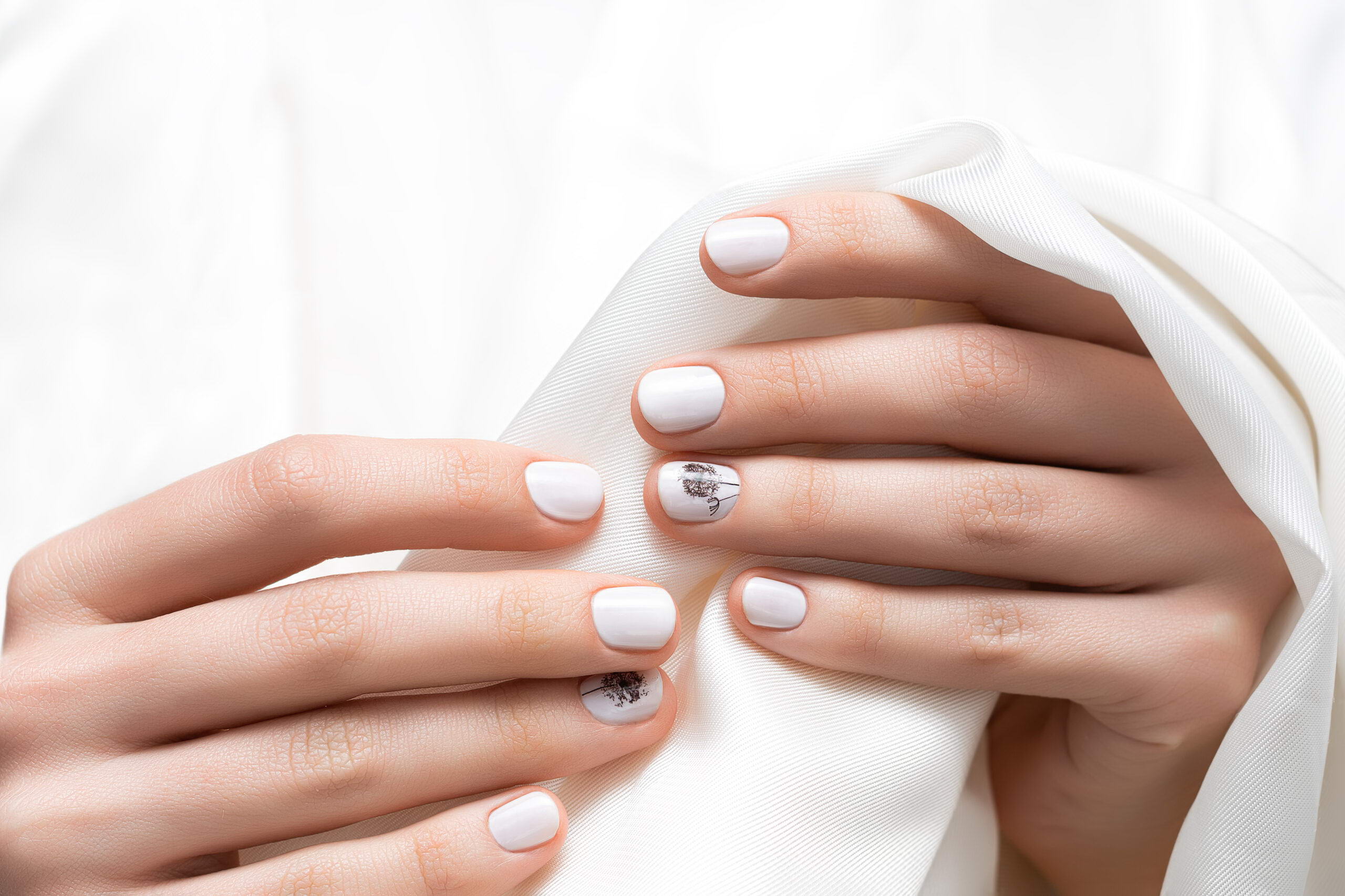 Female hands with white nail design, close up.