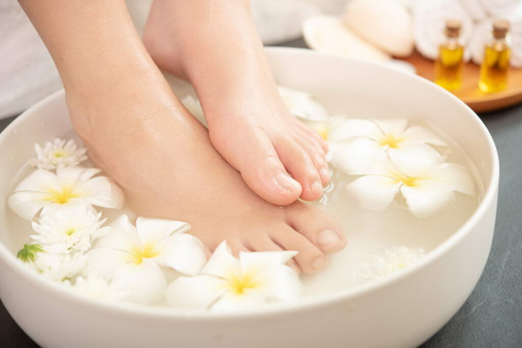 closeup view of woman soaking her feet in dish with water and fl